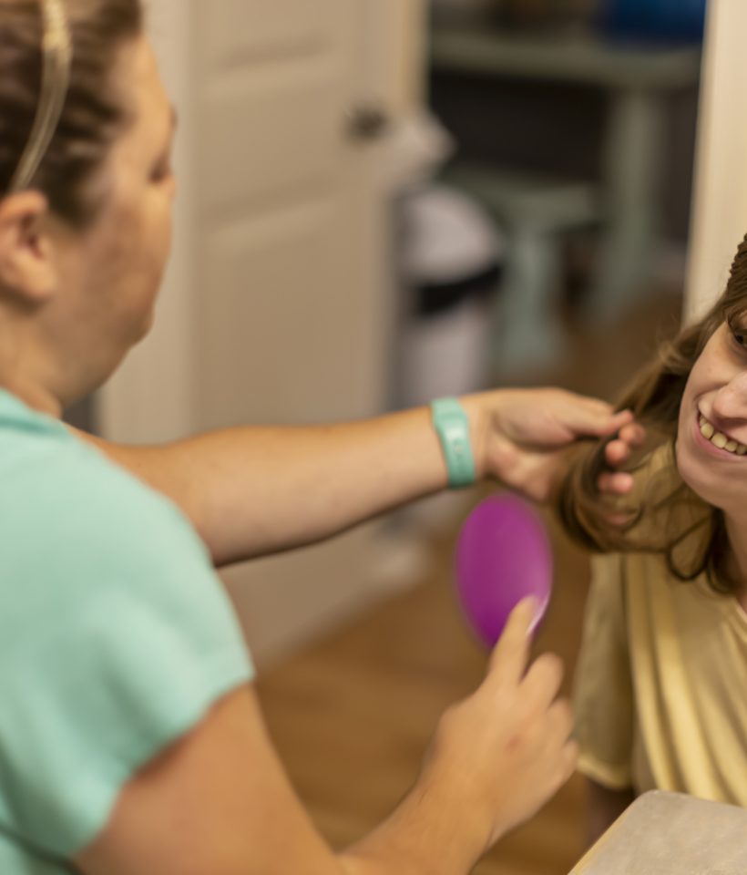 Intellectually disabled young woman needs assistance with all forms of daily living including having her hair brushed every day.