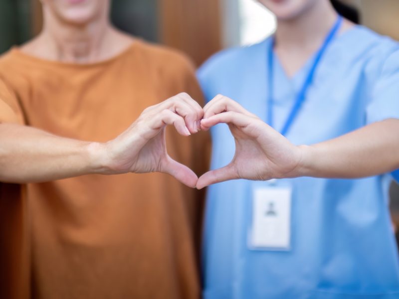 Nurse or caregiver and elderly woman support, healthcare service and health portrait at home. Medical physiotherapy, make a heart shape with your hands together in home.